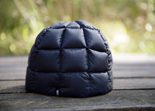 Load image into Gallery viewer, Close-up of the black GOG Down Beanie, showing the quilted dome construction and small GOG logo tab, resting on a wooden picnic table with a blurred green forest background.
